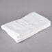 A folded white Oxford Belleeza bath towel on a gray surface.