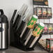 A black Choice countertop cup and lid organizer holding several coffee cups.