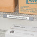 A Metro shelf with gray label holder and boxes labeled "Janitorial Supplies" on it.