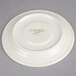 A cream white China saucer with "Oneida" in green writing.