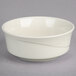 A Oneida Espree cream white china bowl with a wavy design on a gray surface.