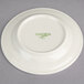 A cream white Oneida bread and butter plate with green writing that says "Oneida"