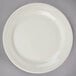 A Oneida cream white china plate with a rim on a gray surface.