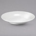 A close-up of a white Oneida Botticelli porcelain pasta bowl on a white surface.
