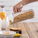 A hand pouring cereal into a Frilich acrylic dry food flute over a glass container.