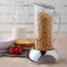 A stainless steel Frilich dispenser base with a glass container of cereal in it.