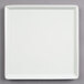 A Frilich white square china display plate on a gray surface.