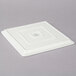 A Frilich white square china display plate with a square design.