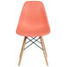 A Flash Furniture peach plastic chair with wooden legs.