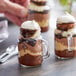 A close-up of a glass jar with chocolate mousse and whipped cream in it.