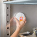 A hand holding a white Arm & Hammer Fridge Fresh container opening a refrigerator door.