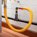 A yellow tube connected to a black pipe with a Regency 48" Mobile Gas Connector Hose.