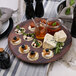 A Rosseto walnut melamine tray with appetizers on a table.