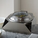 A silver stainless steel chafer stand with a glass lid on it.