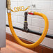A yellow Regency 60" gas connector hose connected to a pipe.