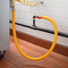 A yellow Regency 60" mobile gas connector hose connected to a black pipe.