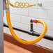 A yellow Regency gas connector hose connected to a pipe.