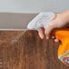 A person spraying Arm & Hammer Hard Surface Cleaner on a wooden table.