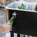 A hand opening a black Choice beverage cooler to put a beer bottle inside.