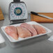 A white foam meat tray with raw chicken breasts on a counter.