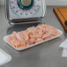 A white foam CKF meat tray of raw chicken on a counter.