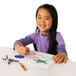 A young girl drawing with a Crayola crayon on a white paper.