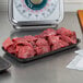 A black foam CKF meat tray on a counter with raw meat.