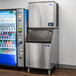 A Manitowoc Indigo NXT air cooled ice machine in a corporate cafeteria next to a soda machine.