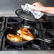 A person cooking chicken in a Lodge cast iron skillet.