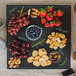 A Tablecraft faux slate melamine display tray with food on a table.