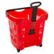 A red plastic shopping basket with black wheels and a black handle.