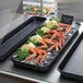 An American Metalcraft black melamine market tray on a counter with crab legs and lemons on ice.