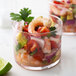 A Spanish style rocks glass filled with a shrimp salad garnished with lime.