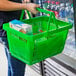 A person holding a green Regency shopping basket with a carton of cereal in it.
