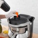 A person using a Hamilton Beach Otto Auto Feed Juice Extractor to juice carrots.