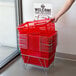 A hand holding a stack of red Regency shopping baskets with a white sign on top.