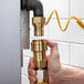 A hand using a Regency quick disconnect fitting to connect a yellow hose to a metal pipe.