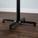 A Lancaster Table & Seating black cast iron bar height table base on a wood floor.