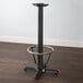 A Lancaster Table & Seating black cast iron bar height column table base with a metal foot ring.