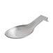 A silver spoon resting on a stainless steel spoon rest.
