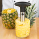 A stainless steel pineapple slicer coring a pineapple.