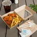 A Bagcraft Eco-Flute take-out box with chicken and fries on a table with a drink and a straw.