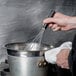 A person using a Matfer Bourgeat stainless steel whisk in a pot.