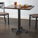 A Lancaster Table & Seating black cast iron table base with glasses of beer on it.