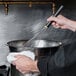 A person holding a Matfer Bourgeat stainless steel whisk in a bowl.