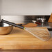 A Matfer Bourgeat stainless steel whisk with an Exoglass handle on a cutting board.