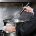 A person using a Matfer Bourgeat stainless steel whisk in a bowl.