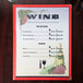 Menu cover with a grapevine design on a table with a wine glass and grapes.