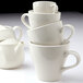 A stack of Tuxton white Europa cappuccino mugs.