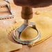 A hand using a Fox Run metal ravioli cutter to cut dough.